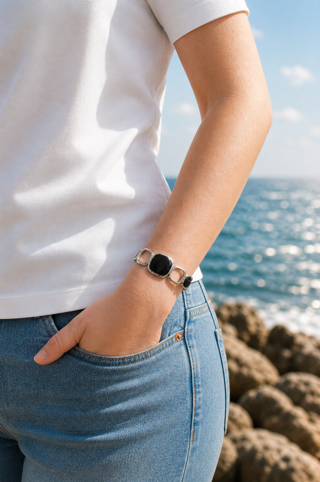 Stainless steel cuff bracelet with geometric open links and dark stone-inspired accents worn on the coast in Hanko, Finland