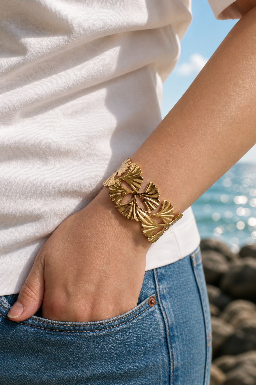 Gold-tone botanical cuff bracelet with organic leaf-inspired openwork details worn on the coast in Hanko, Finland