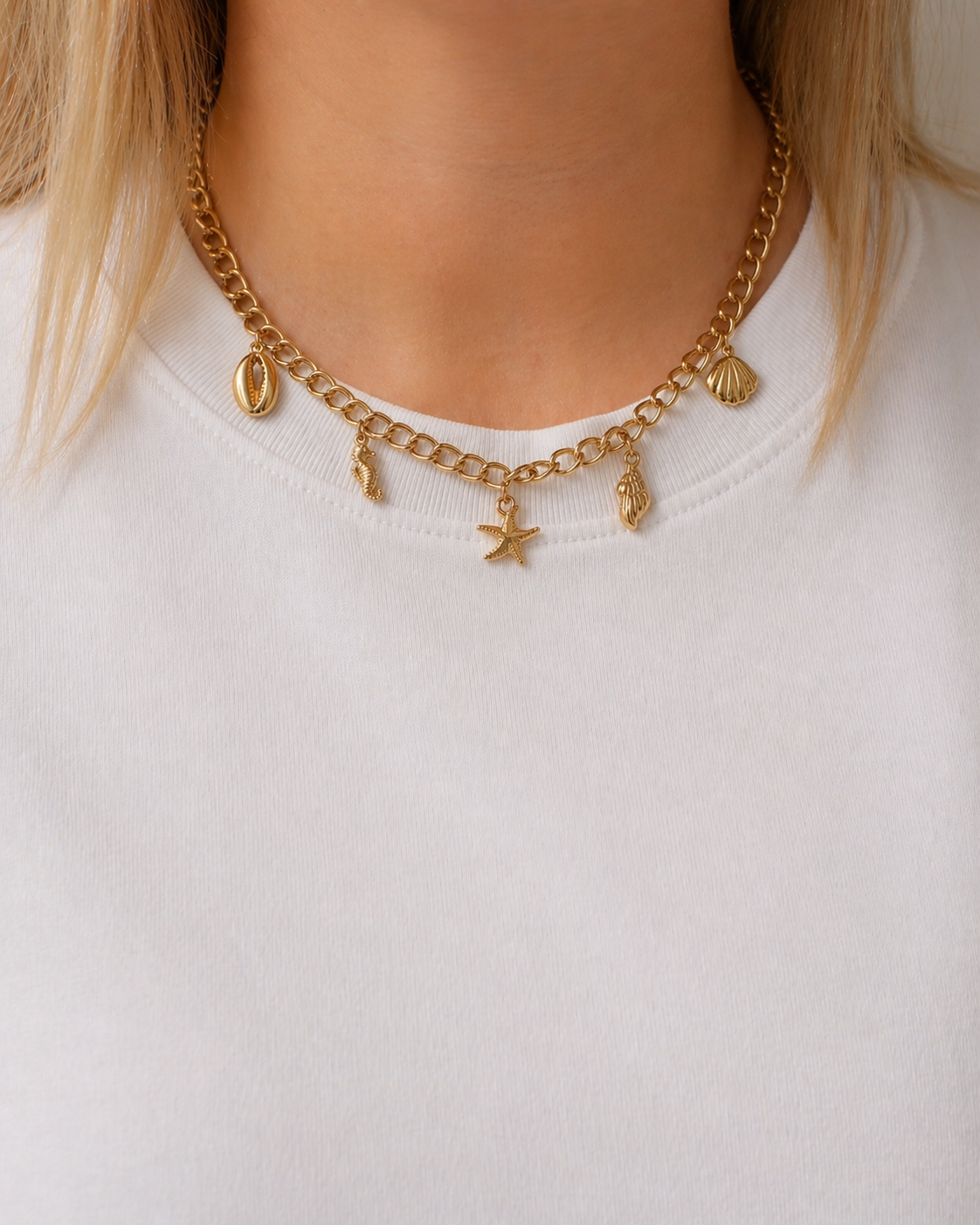 Gold-tone charm chain necklace with starfish, shell and seahorse charms worn by a model by HNKO