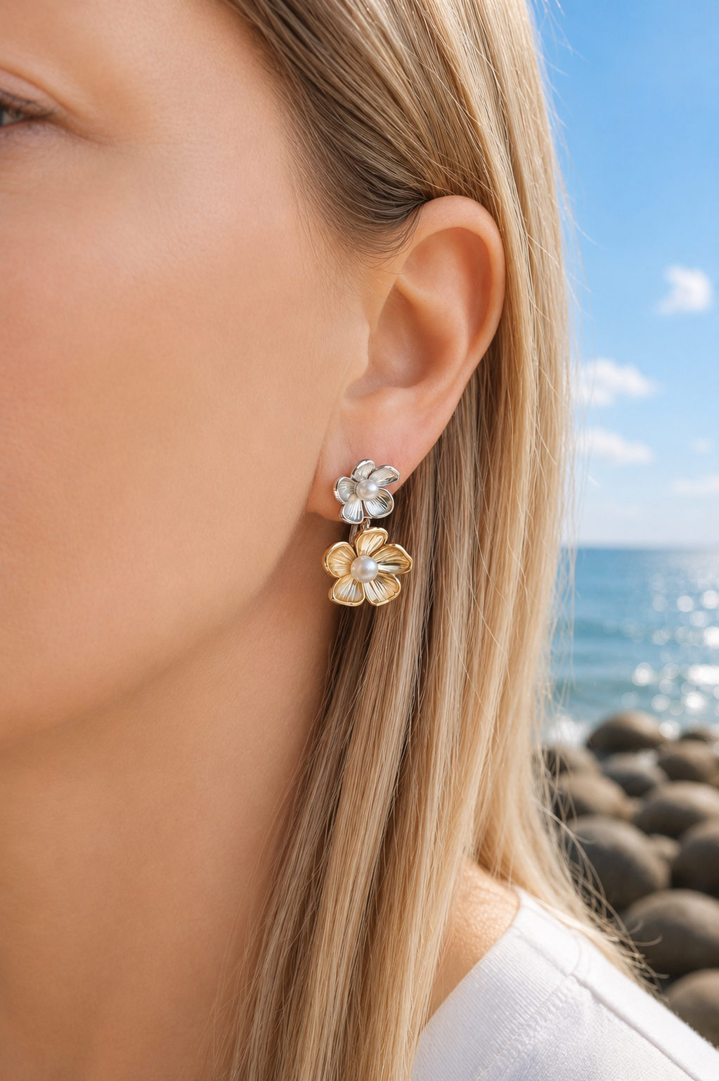 Close-up of a person wearing a floral earring with a beach in the background