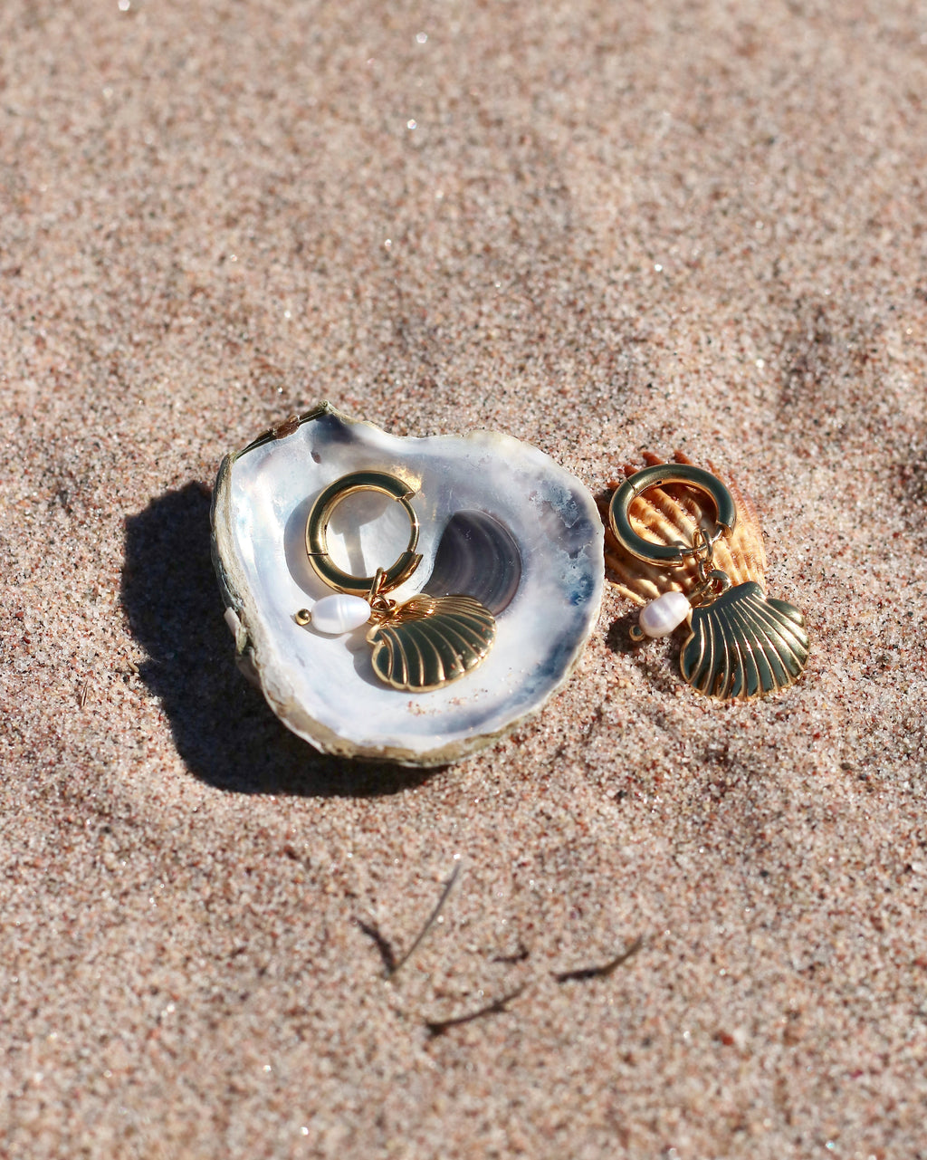 Gold hoop earrings with a shell charm and small pearl drop.