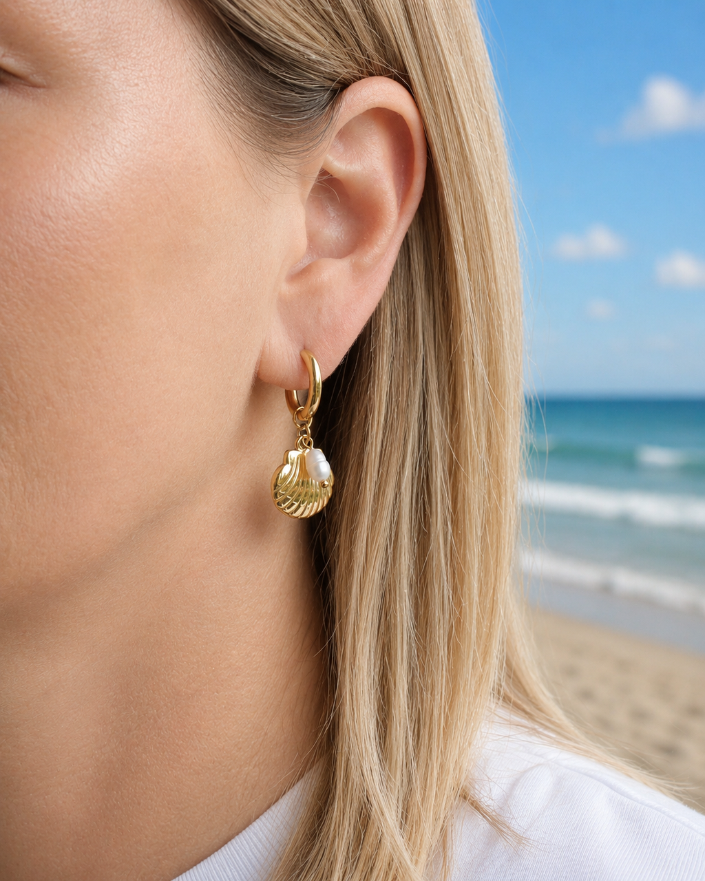 Gold-tone hoop earrings with seashell charms and freshwater pearl accents worn on the coast in Hanko, Finland