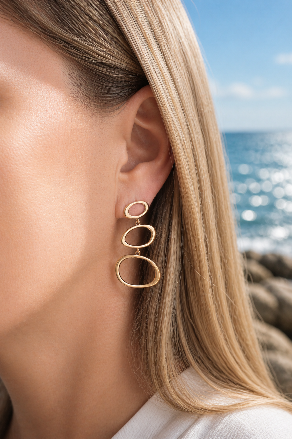 Gold-tone organic link drop earrings with sculptural open oval forms worn on the coast in Hanko, Finland