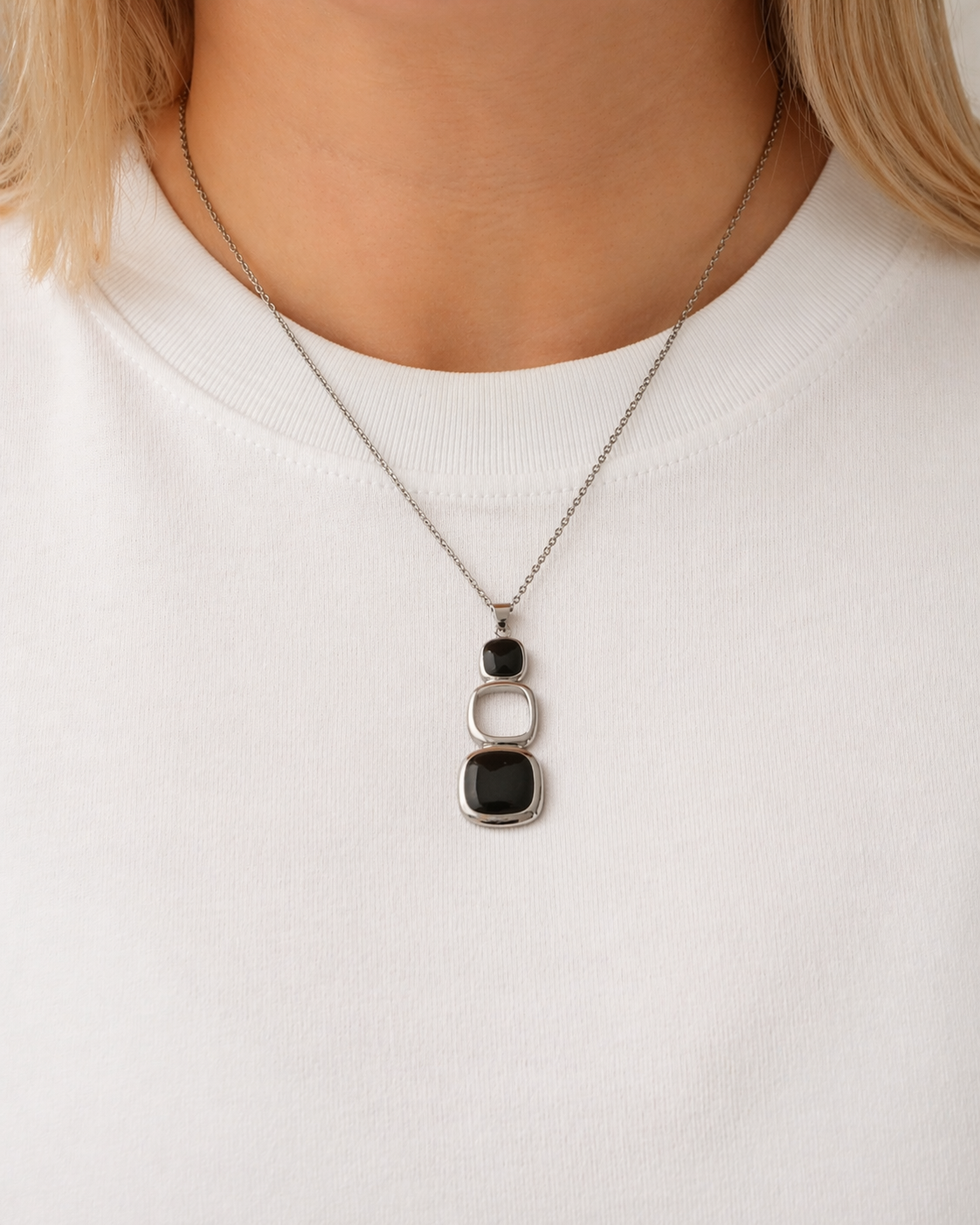 Link pendant necklace in polished stainless steel worn on a chain, featuring sculptural geometric forms by HNKO