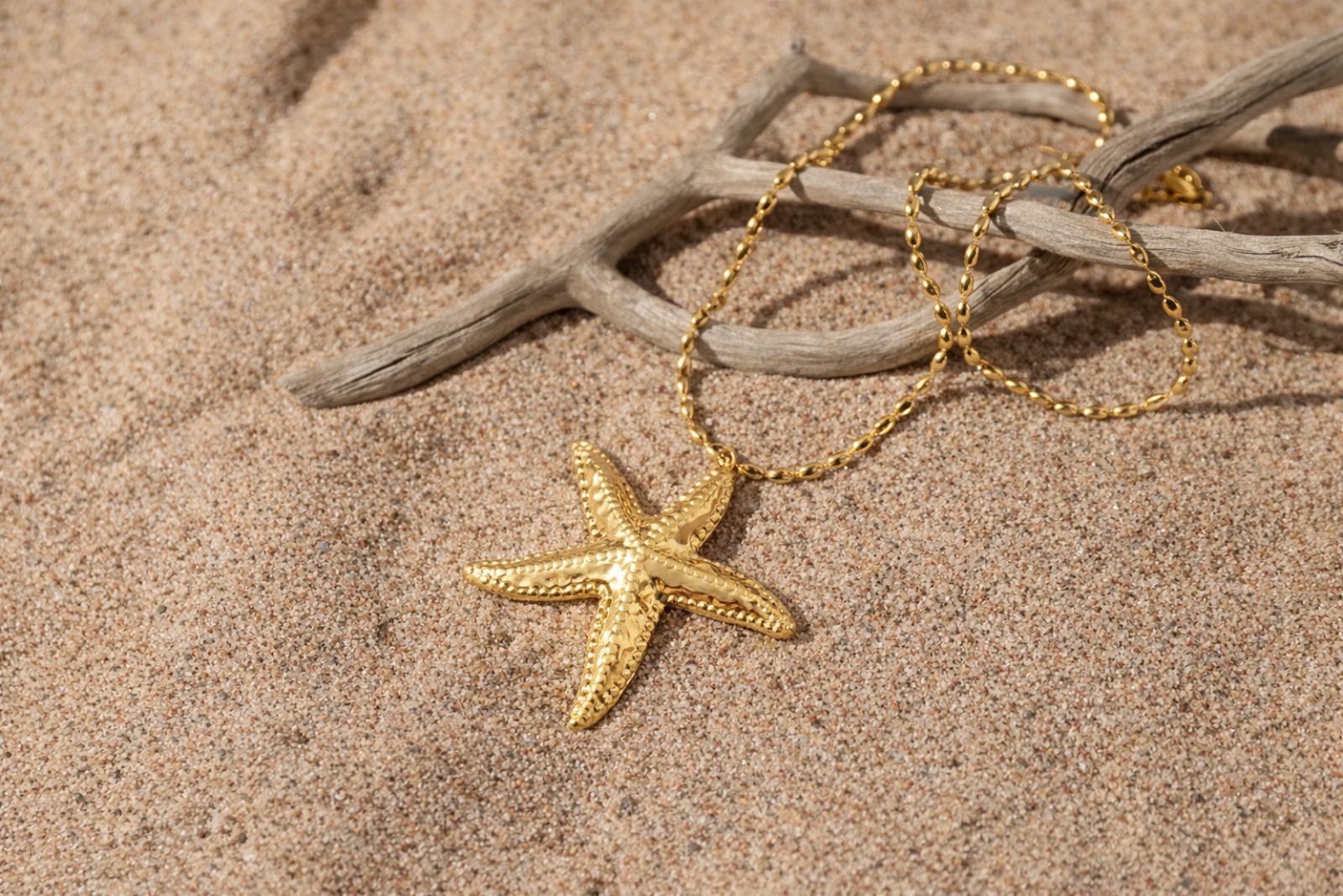 Gold-tone starfish pendant necklace displayed on beach sand, inspired by Nordic coastal life in Hanko, Finland by HNKO