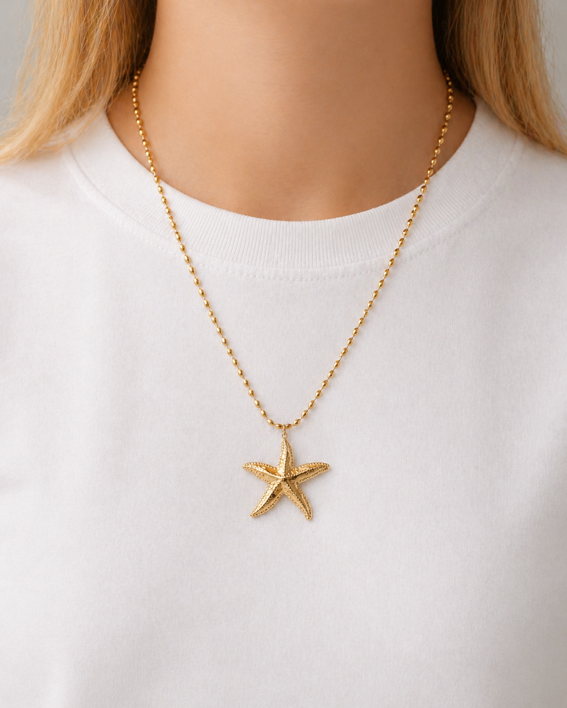 Model wearing HNKO starfish pendant necklace in gold-tone stainless steel