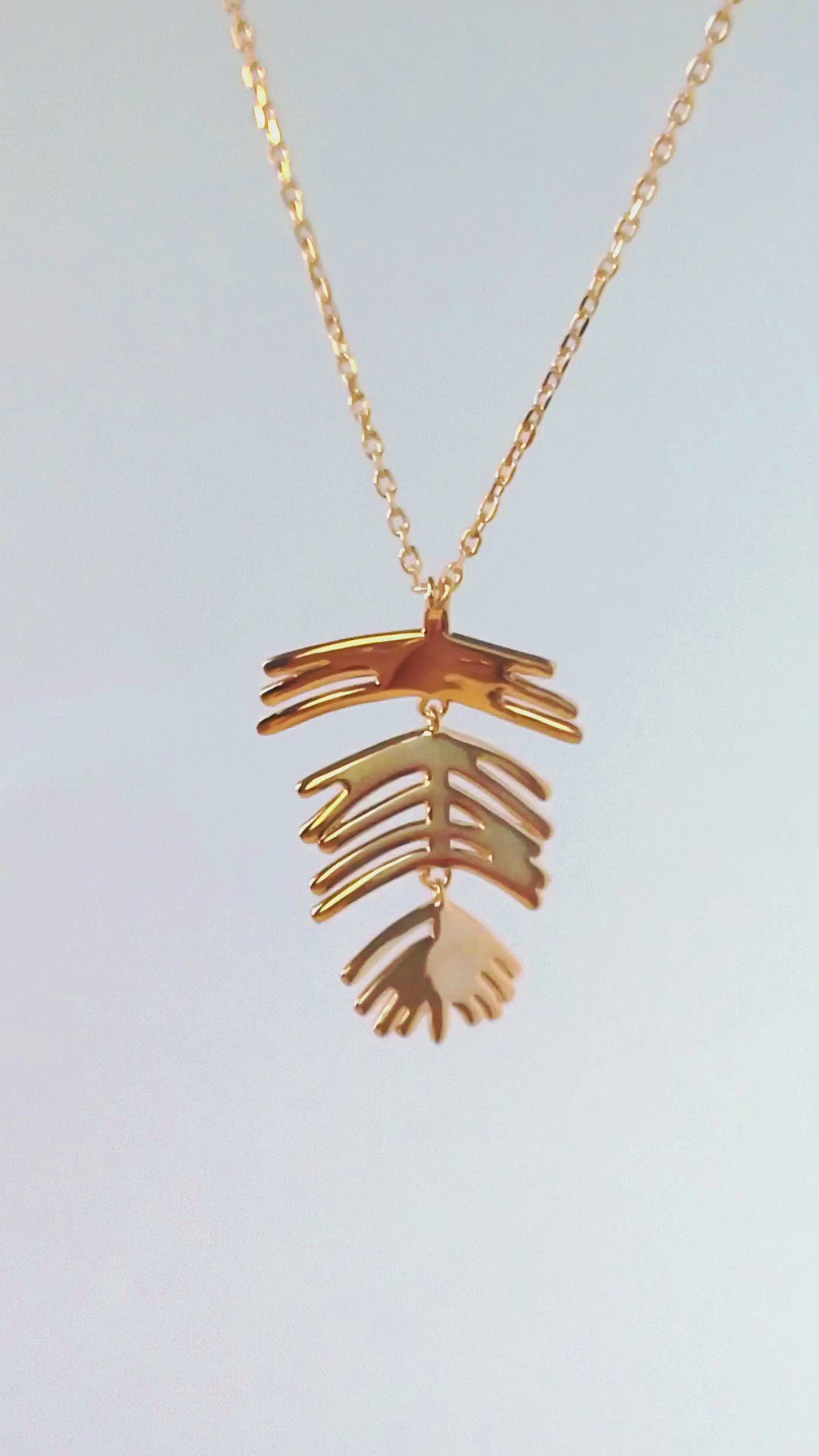 Close-up video of 18K gold plated articulated leaf necklace by HNKO Finland, showing soft natural movement of layered leaf elements as they catch light and shift fluidly with motion