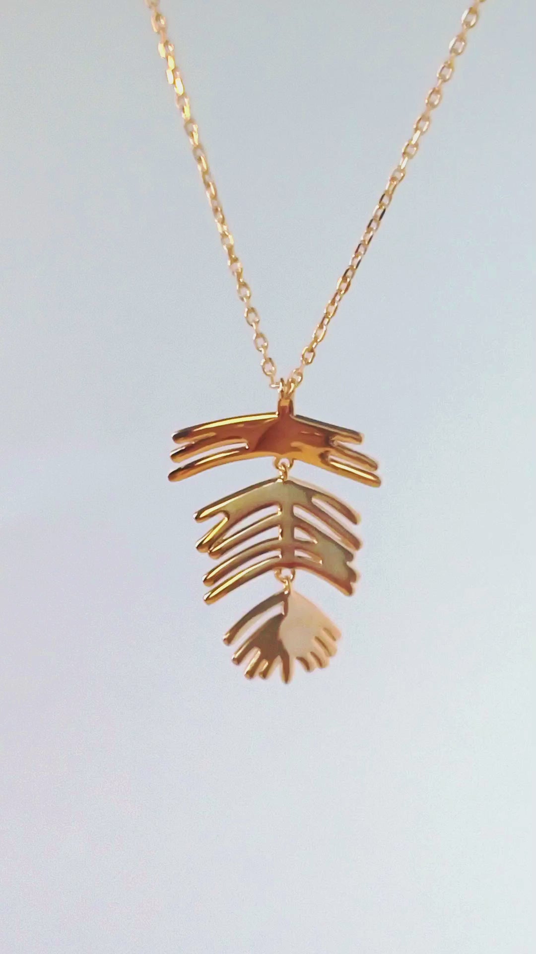 Close-up video of 18K gold plated articulated leaf necklace by HNKO Finland, showing soft natural movement of layered leaf elements as they catch light and shift fluidly with motion